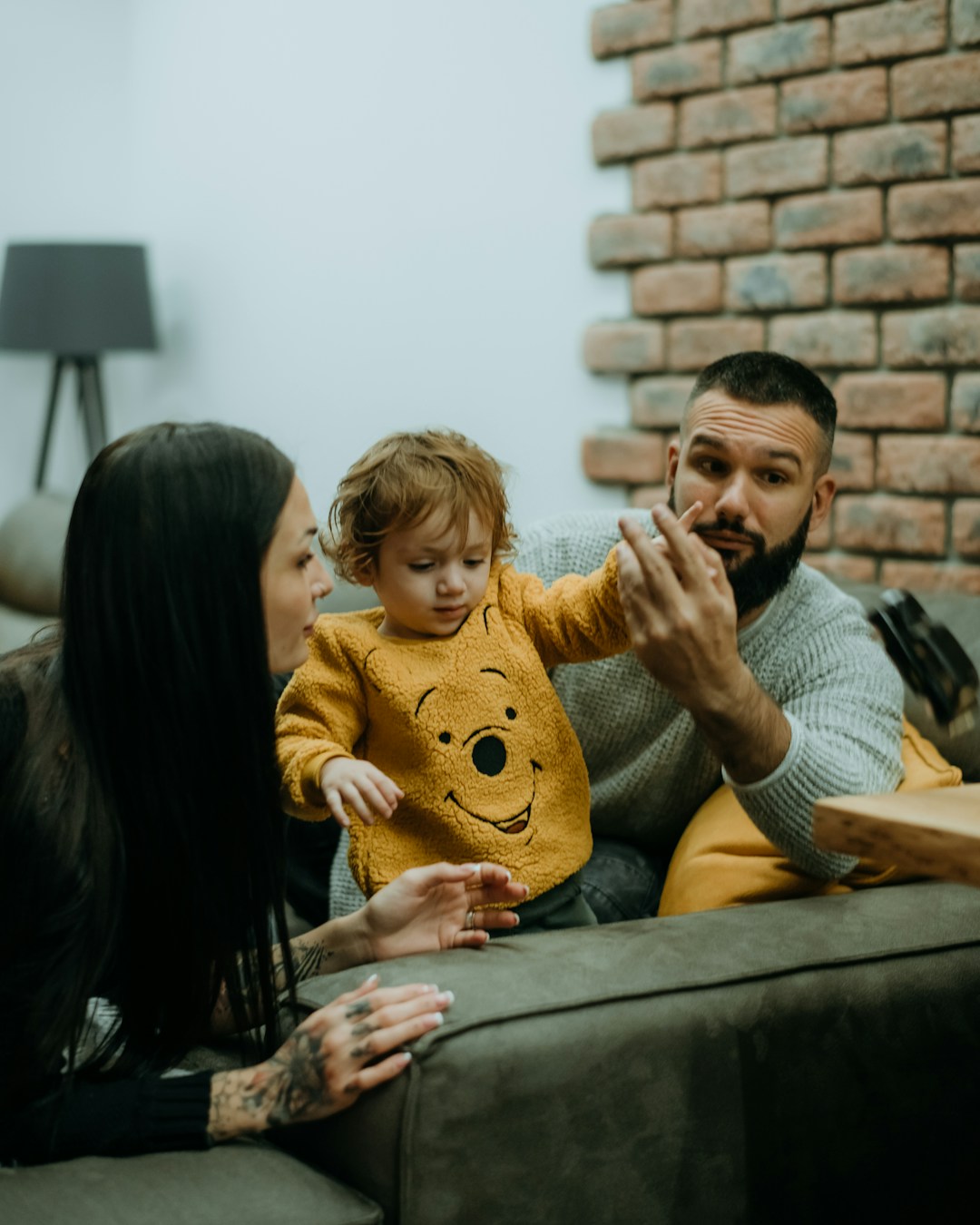 a man, woman and child sitting on a couch, parent child home routine